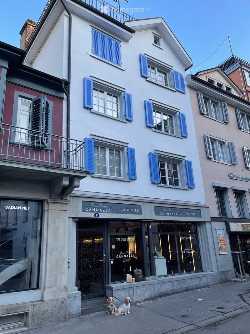 3 story building, blue shutters, brick walls, commercial storefront, balcony on top floor, red brick rooftop