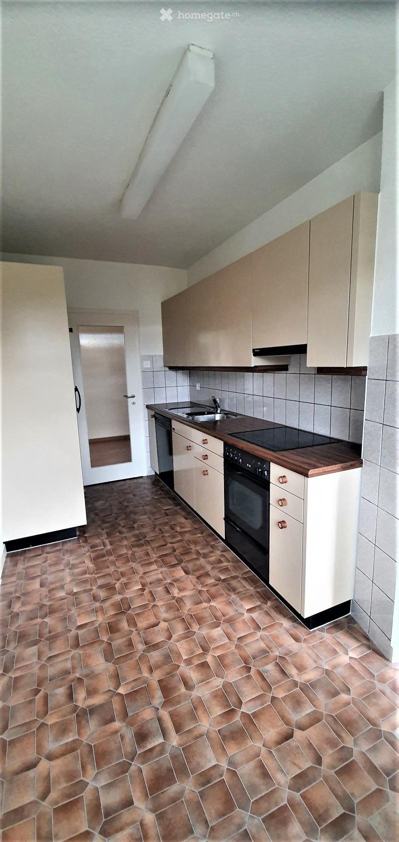 Modern kitchen with light-colored cabinets, a wooden countertop, and a tiled floor. Features include a sink, faucet, oven, and dishwasher.