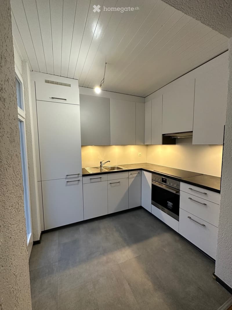 Modern kitchen with white cabinets, stainless steel sink, faucet, and oven. Features under-cabinet lighting and a sleek, minimalist design.