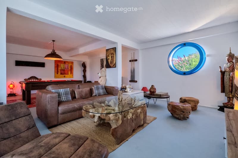 Modern living room with a large sectional sofa, glass coffee table, ottoman, and decorative items including a statue and artwork.