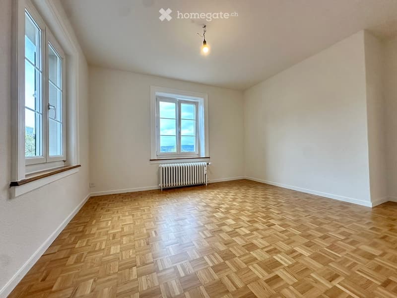 empty room, wooden parquet floor, white walls, two windows, radiator, wooden window sills, ceiling lamp