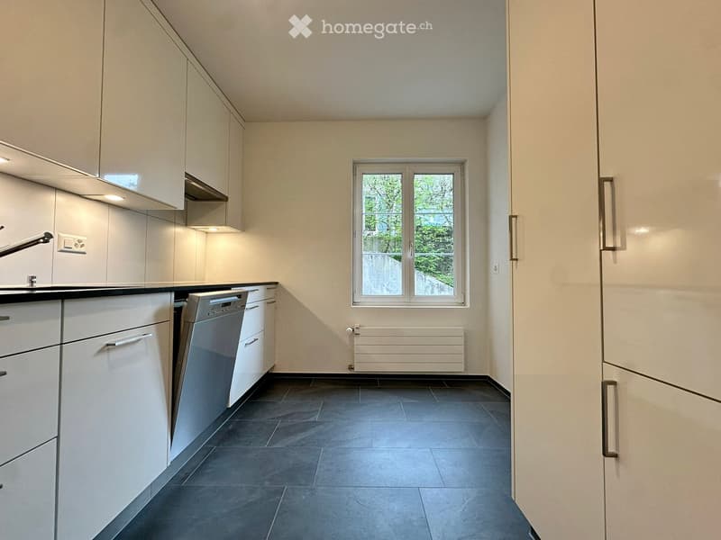 modern kitchen with white cabinets, black tiled floor, stainless steel dishwasher, window with view