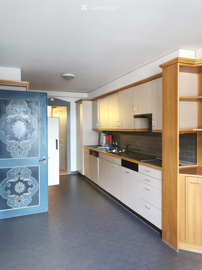 Spacious kitchen with white cabinets, wooden countertops, and black tile backsplash. The kitchen features a dishwasher and has a decorative blue door with intricate patterns.