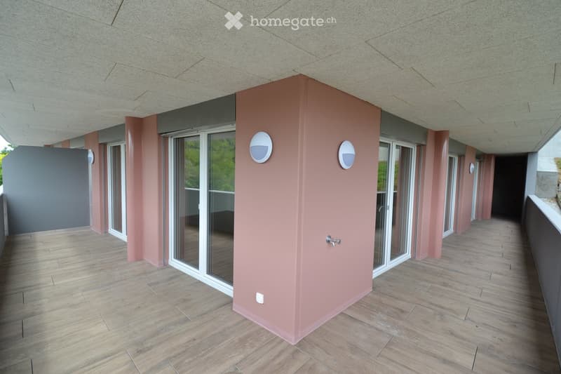 Modern hallway with wooden flooring, pink walls, glass doors, and integrated lighting fixtures.
