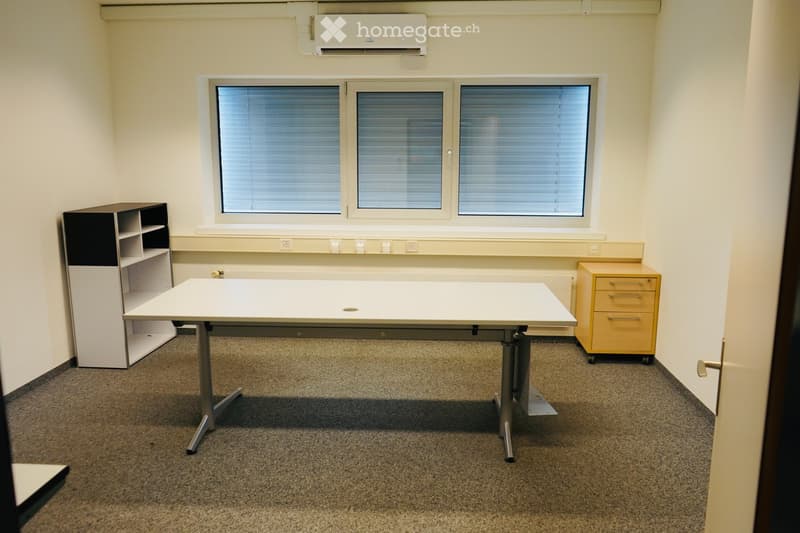 Office space with a large white table, a black and white shelving unit, and a yellow rolling cabinet.