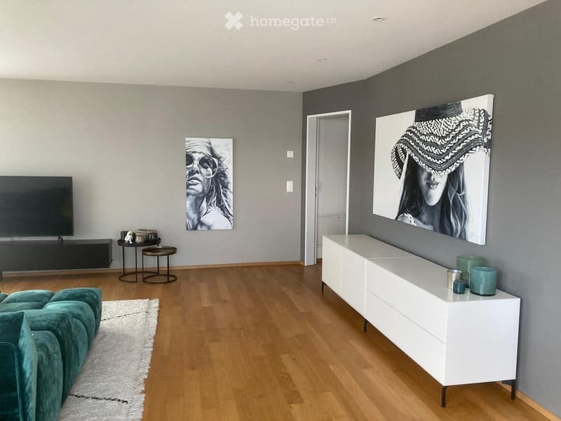 Modern living room with a teal sofa, white console table, two small stools, a TV, and two large picture frames on the walls.