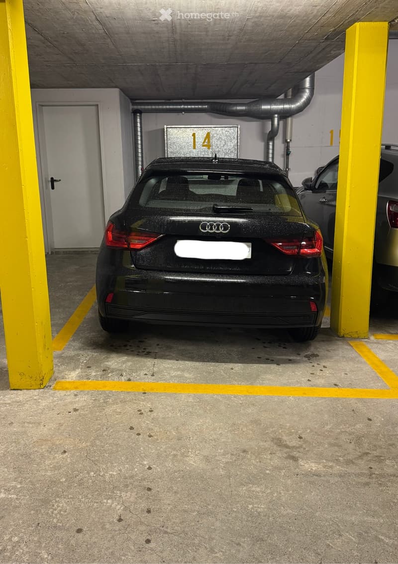 Underground parking area with concrete floors, yellow pillars, and two parked cars, including an Audi.