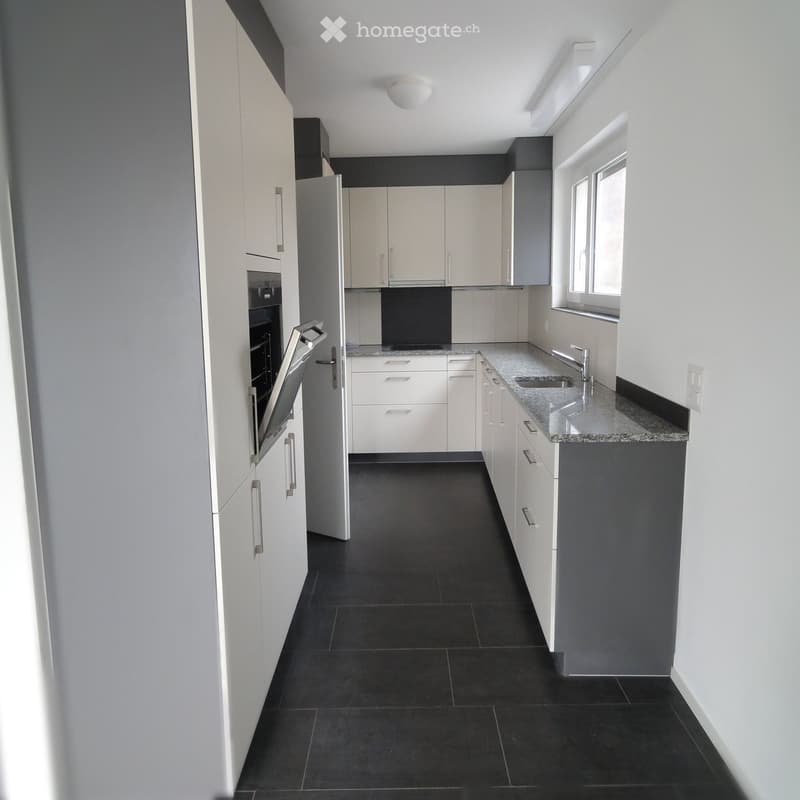 Modern kitchen with white cabinets, granite countertop, black tiled floor, and stainless steel sink and faucet.