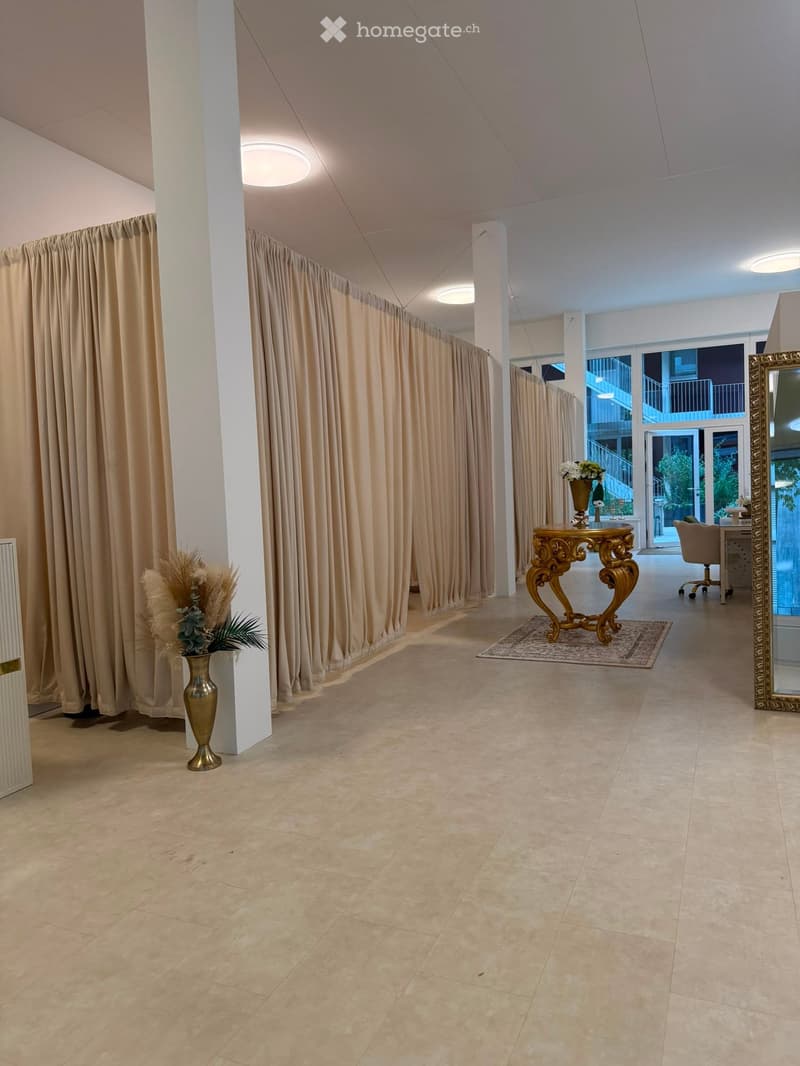 Elegant hallway with beige curtains, a small ornate table with a vase, a large mirror, and a view of a balcony area.