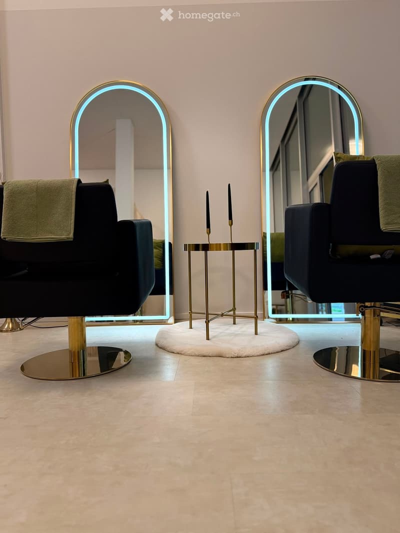 Modern interior with two black chairs, round mirrors with illuminated frames, a small round table with candles, and a plush white rug.