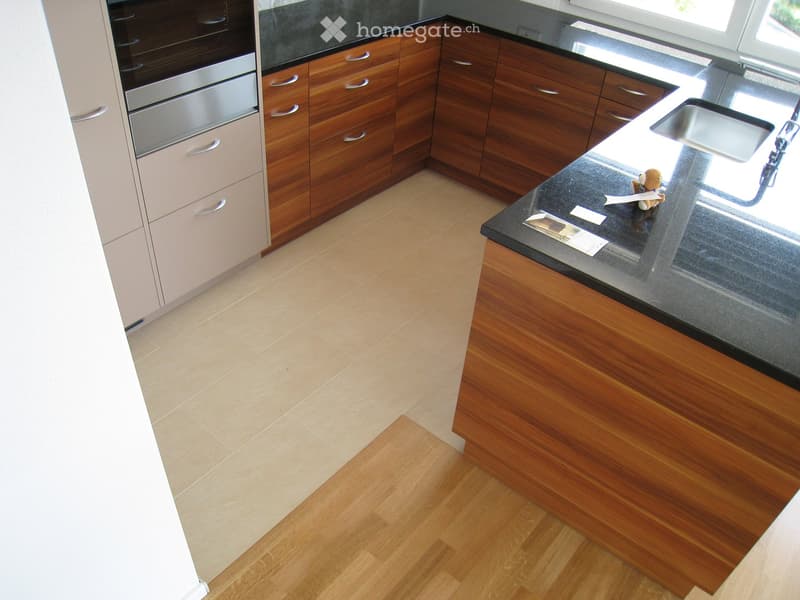 Modern kitchen with wooden cabinets, stainless steel appliances, and a black countertop.
