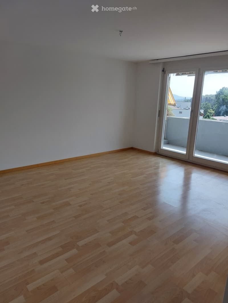 Empty room with wooden flooring and large sliding glass doors leading to a balcony.