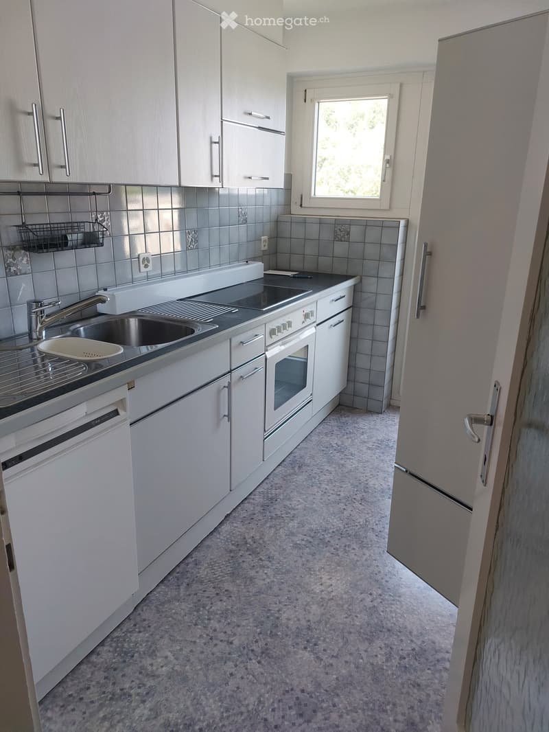 Modern kitchen with white cabinets, stainless steel appliances, and a tiled backsplash. Features a sink, oven, dishwasher, and a window letting in natural light.