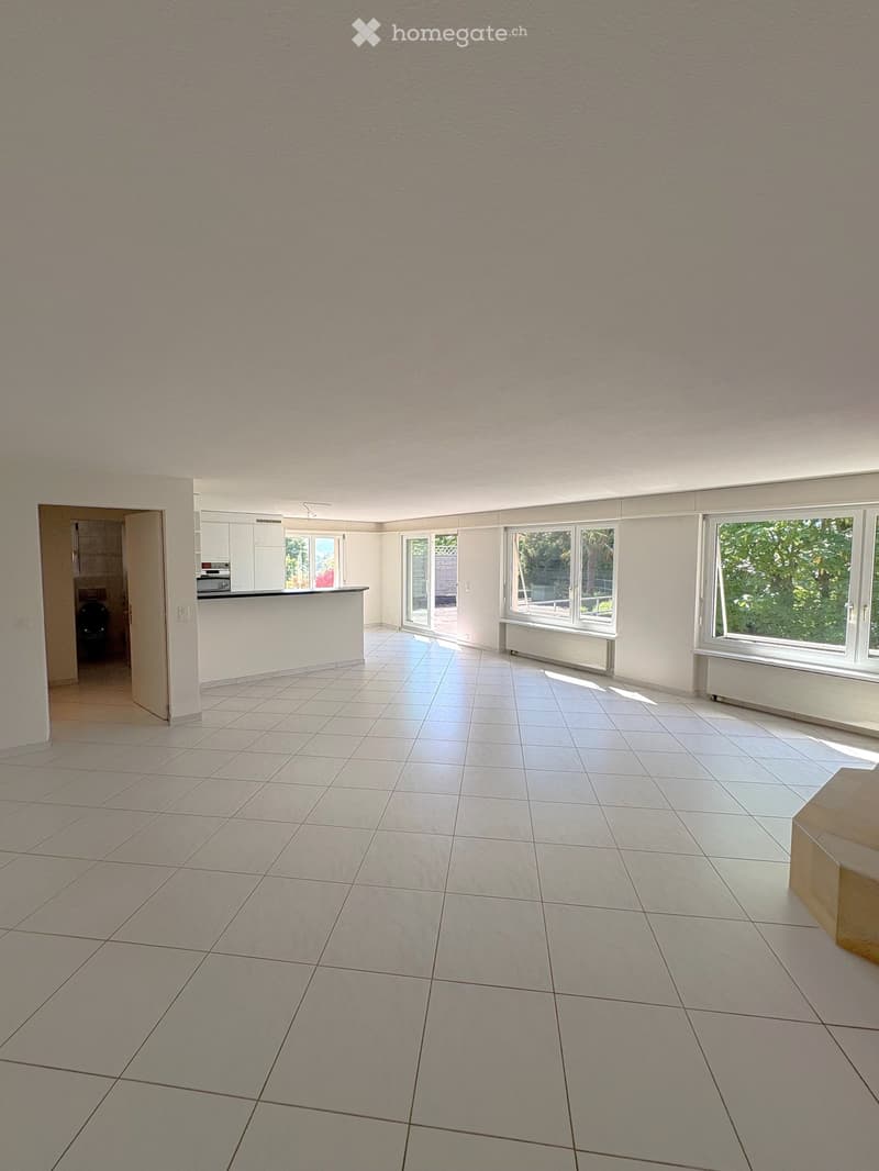 Empty room with tiled floor, white walls, large windows, and an open doorway leading to another room.