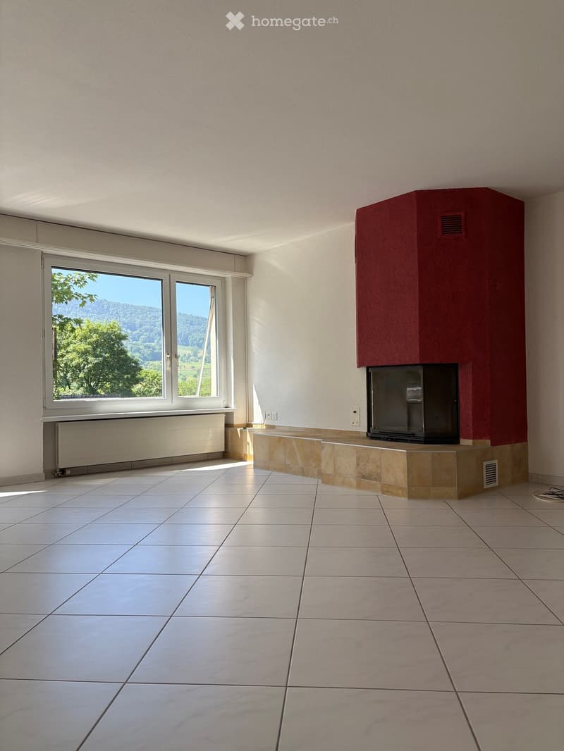 Empty room with tiled floor, fireplace, large window with scenic view, radiator, and power outlets.