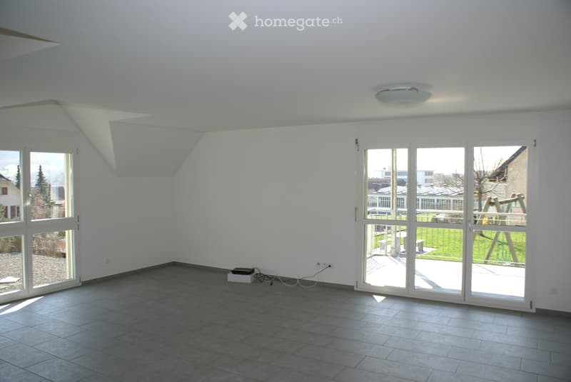 Empty room with large windows and sliding glass doors leading to a balcony, tiled floor, white walls, and a ceiling light fixture.