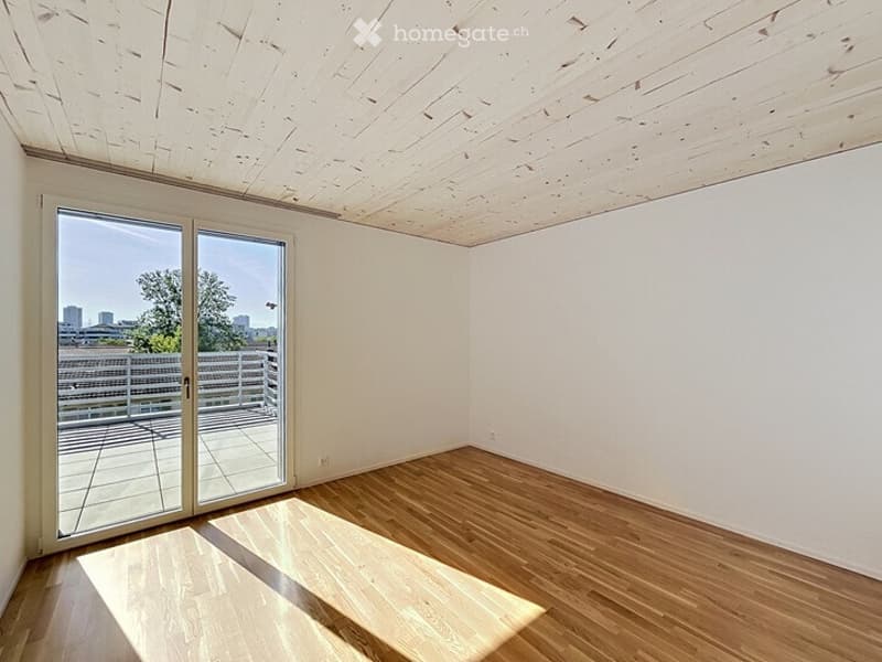 Empty room with wooden flooring, white walls, and large sliding glass doors leading to a balcony.