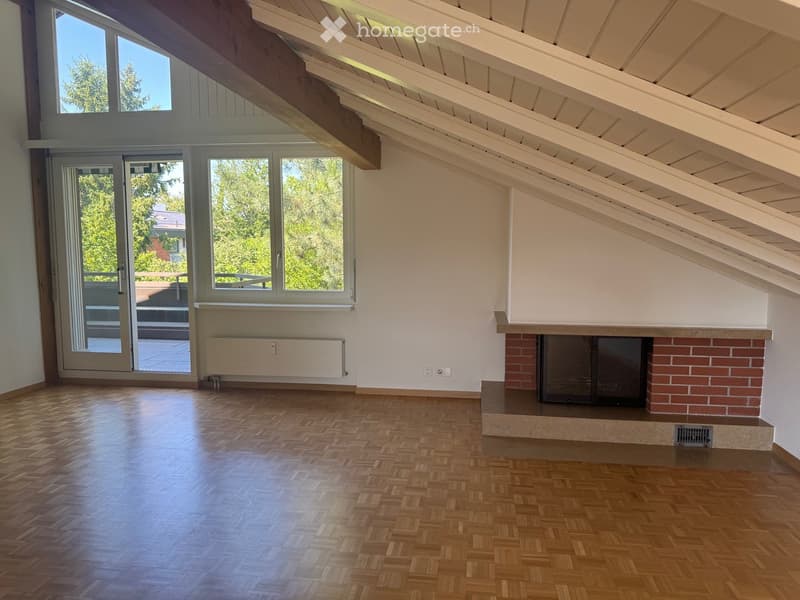 Empty room with wooden flooring, white walls, large windows, and a brick fireplace. No furniture or equipment present.