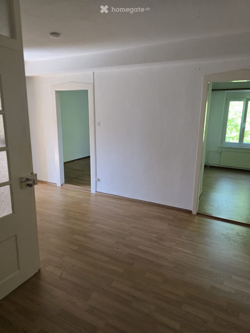 Empty hallway with wooden flooring, white walls, and two open doorways leading to other rooms.