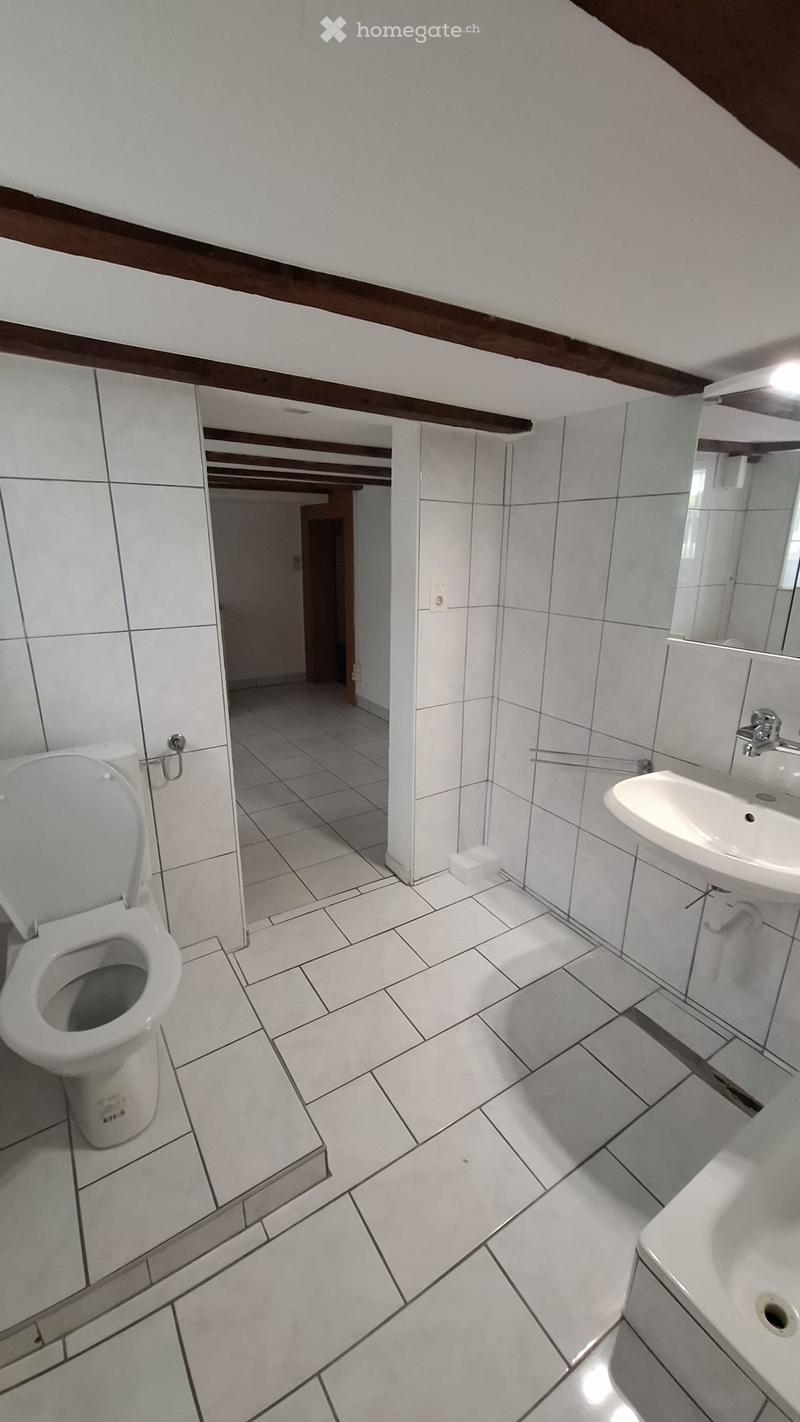 white tiles, toilet, sink, bathtub, mirror, white walls, exposed beams
