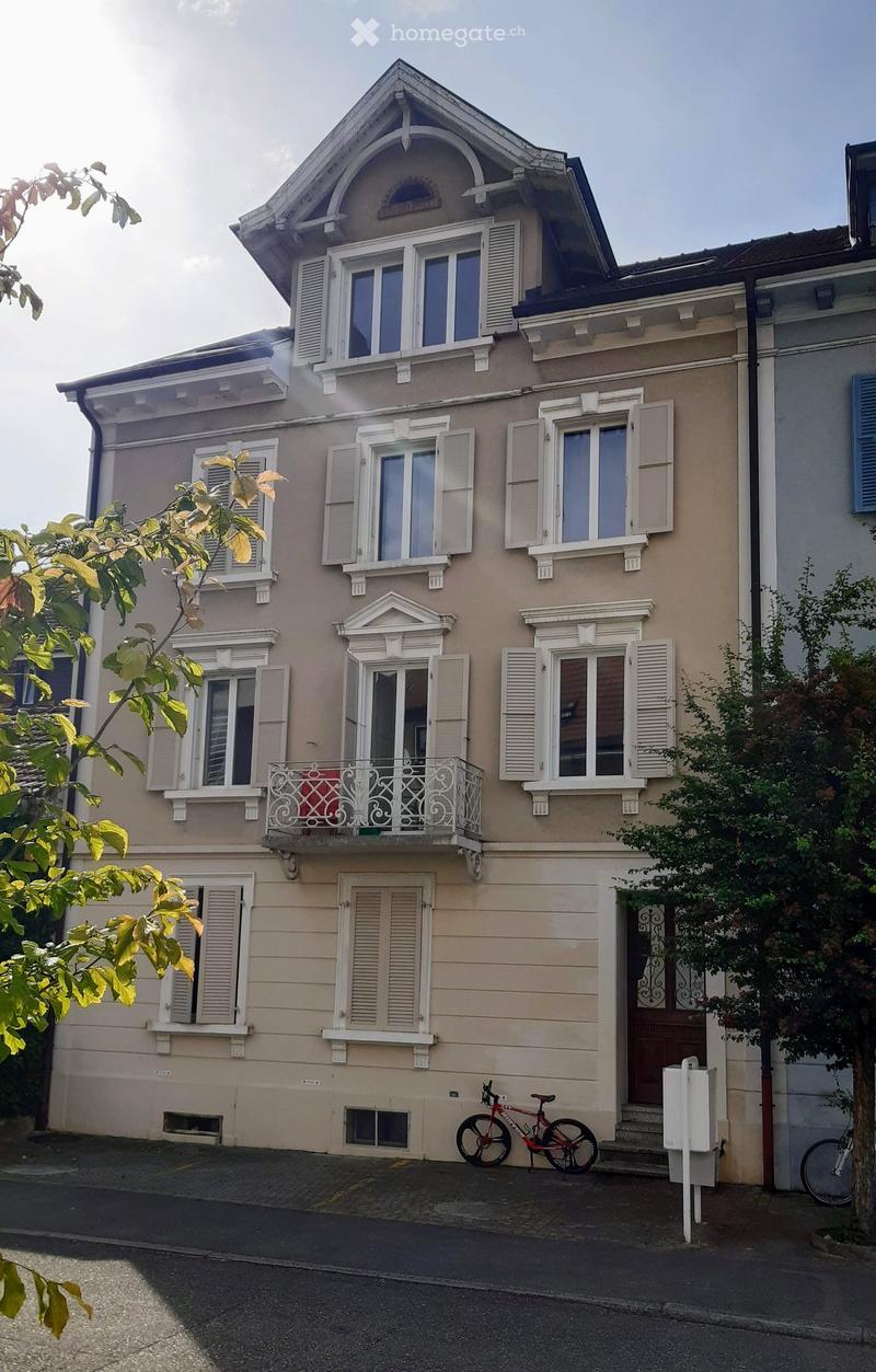 3 story house, beige, white shutters, brown door, balcony, bicycles