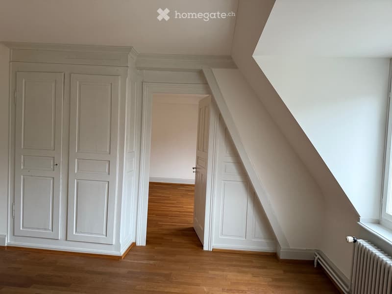 Empty hallway with wooden flooring, white walls, and multiple doors leading to other rooms.