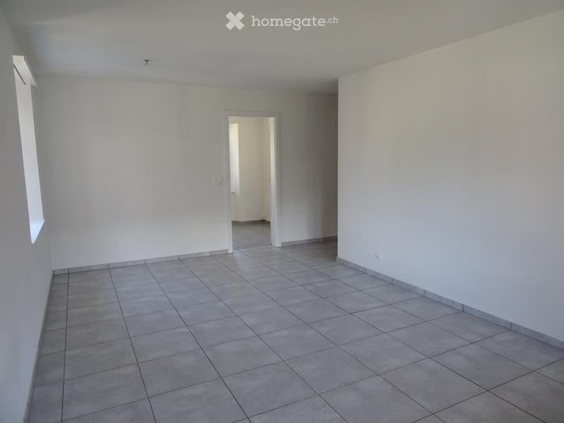 Empty room with tiled floor and white walls, featuring a doorway leading to another space.
