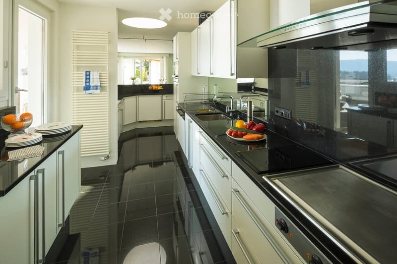 modern kitchen with black tiles, white cabinets, black countertops, stainless steel appliances, large windows