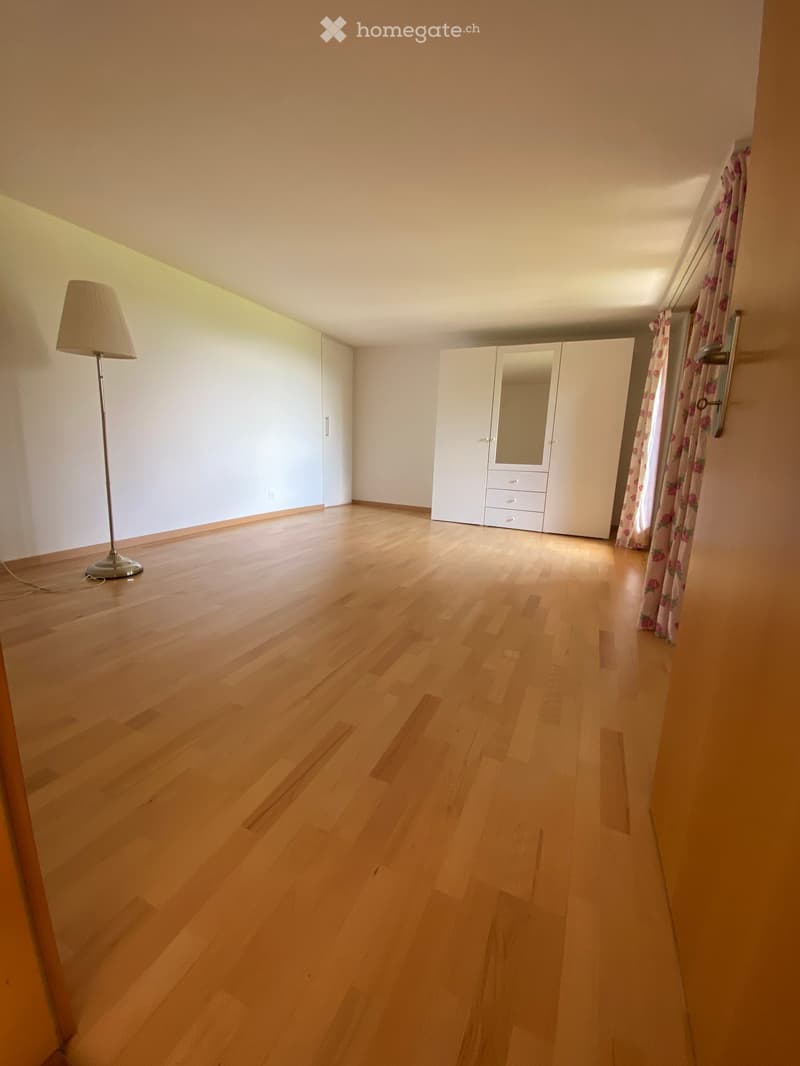 Empty room with wooden flooring, white walls, built-in wardrobe, and a floor lamp near the wall.