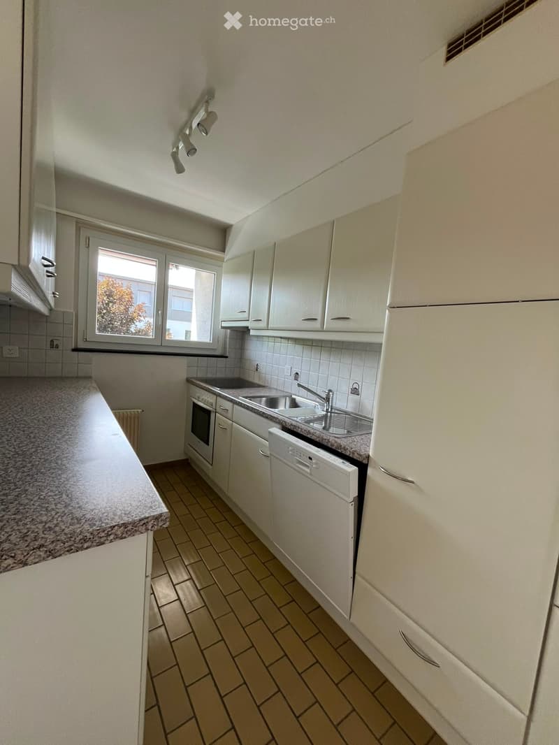 Modern kitchen with white cabinets, granite countertops, tiled backsplash, and stainless steel appliances including a sink, oven, and dishwasher.