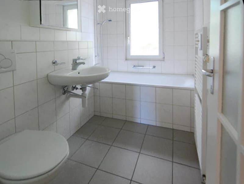 White tiles, bathtub, sink, toilet, showerhead, mirror, towel rack