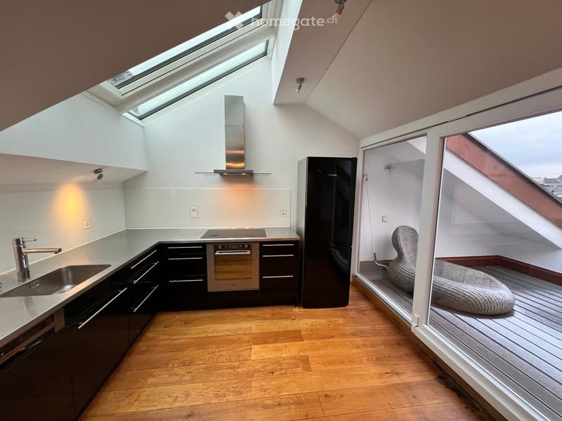Open kitchen, with a stove, oven, fridge, sink, faucet, dishwasher, wooden floors, white walls, and glass doors leading to a balcony.