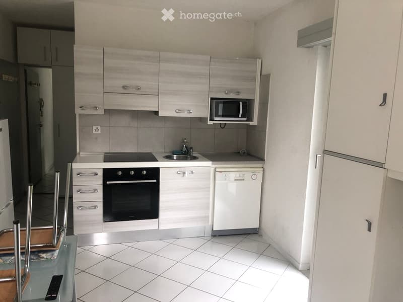 Modern, white kitchen with stainless steel and black appliances. Tiled flooring and fitted cabinets. Open shelves above kitchen worktop. Built-in dishwasher and microwave. Stainless steel oven and gas hob. Tiled backsplash. Tiled flooring. White kitchen i