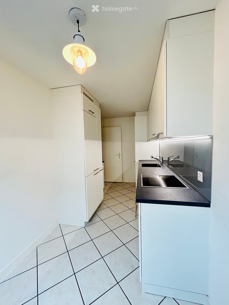 Modern kitchen with white cabinets, stainless steel sink, and pendant light fixture.