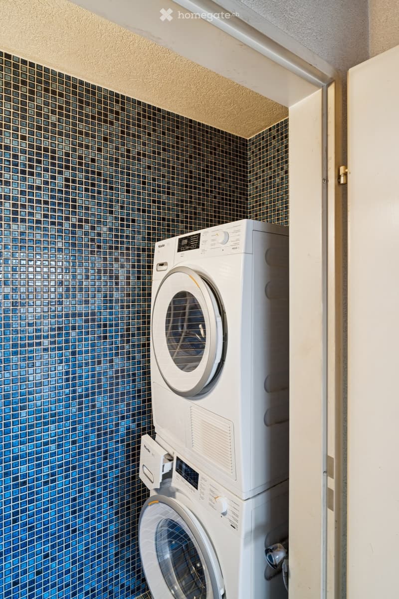 tiled wall, a washing machine and dryer placed next to the wall