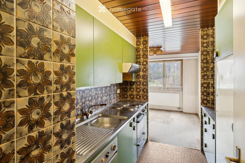 A modern kitchen with green cabinets, tiled walls with flower design, stainless steel sink, oven, and stove, along with a dishwasher