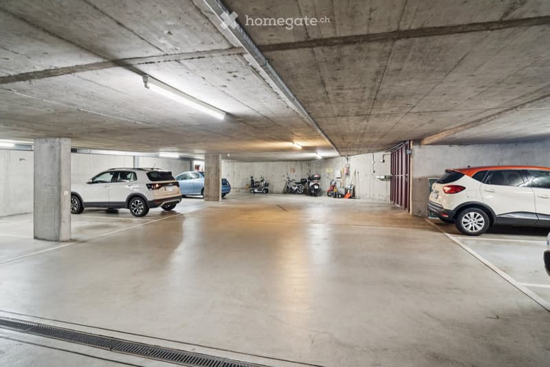 underground parking lot with two cars, two scooters, and one moped