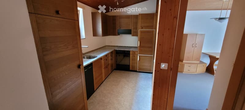 Modern kitchen with wooden cabinets, granite countertop, sink, fridge, oven, and a small dining table.