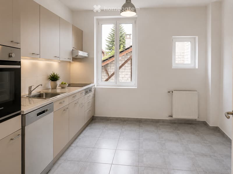 Modern kitchen with light-colored cabinets, stainless steel appliances, a sink, and a window overlooking a staircase area.