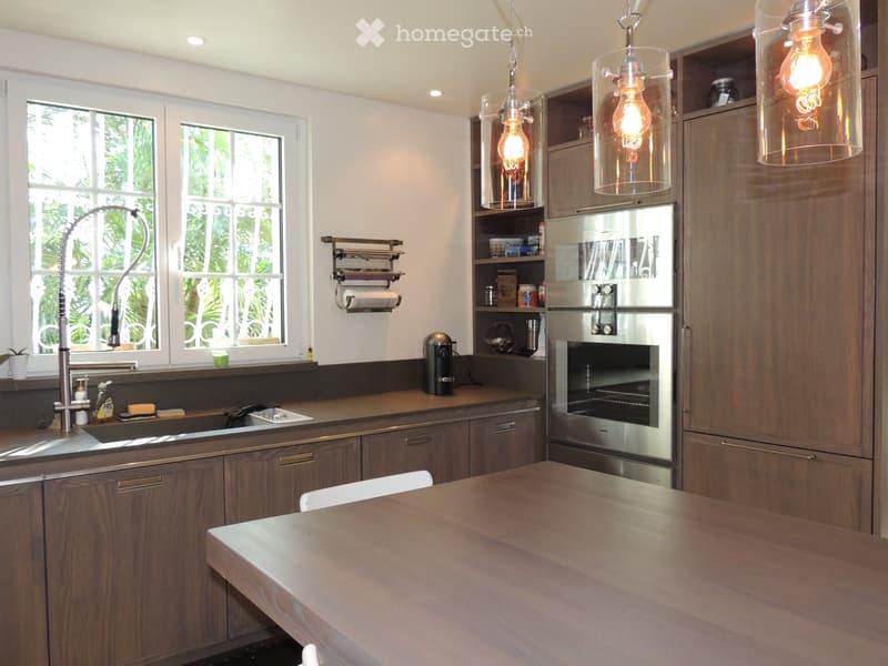 Modern kitchen with wooden cabinets, stainless steel appliances, a central island, and pendant lights.