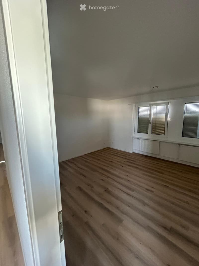 Empty room with wooden flooring, white walls, and two windows with blinds. No furniture or equipment present.
