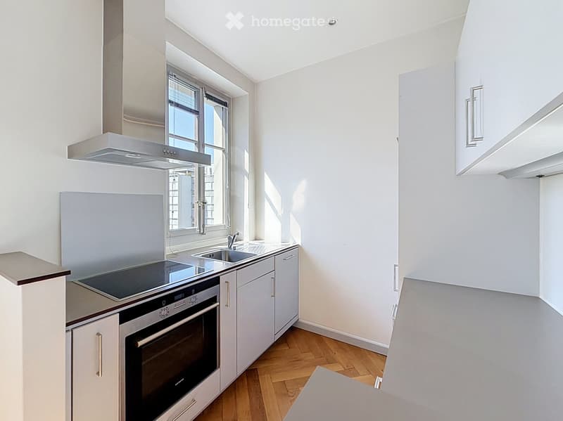 Modern kitchen with white cabinets, stainless steel appliances, and wooden flooring.