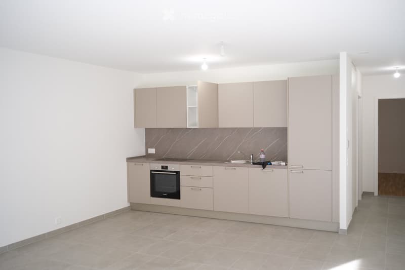 Modern kitchen with light-colored cabinets, a built-in oven, a sink, and a faucet. The backsplash features a marble-like pattern, and the floor is tiled.