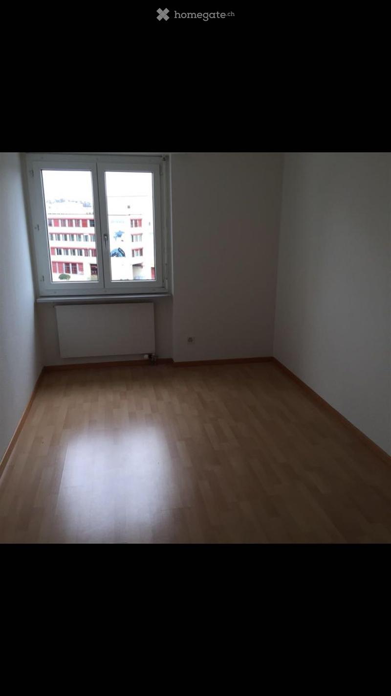 Empty room with wooden flooring, white walls, and a large window with a radiator below it.