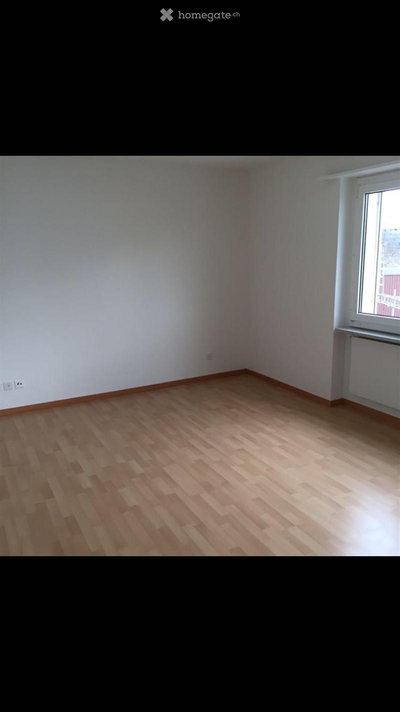 Empty room with wooden flooring, white walls, and a single window with a radiator below it.
