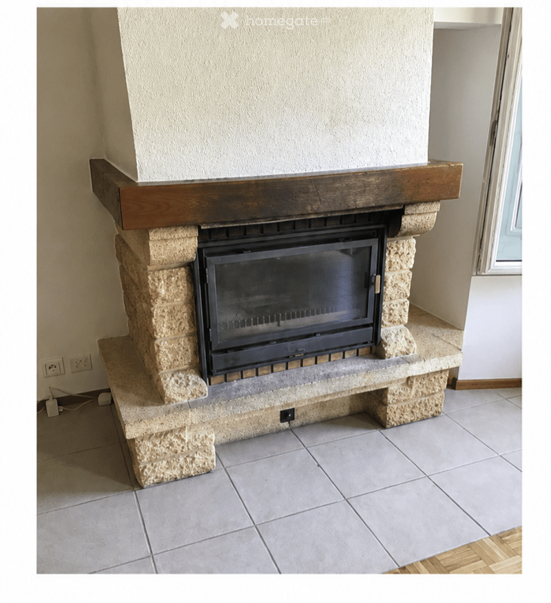 A modern fireplace with a stone surround and wooden mantel, set into a tiled floor area.