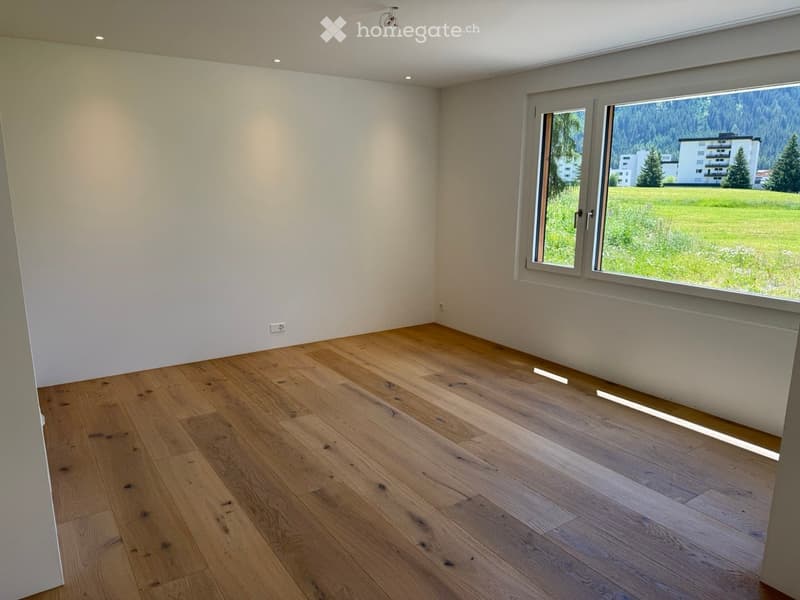 Empty room with wooden flooring, large windows, and white walls.