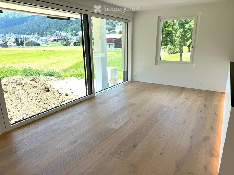 Empty room with wooden flooring, large sliding glass doors, and scenic mountain view.