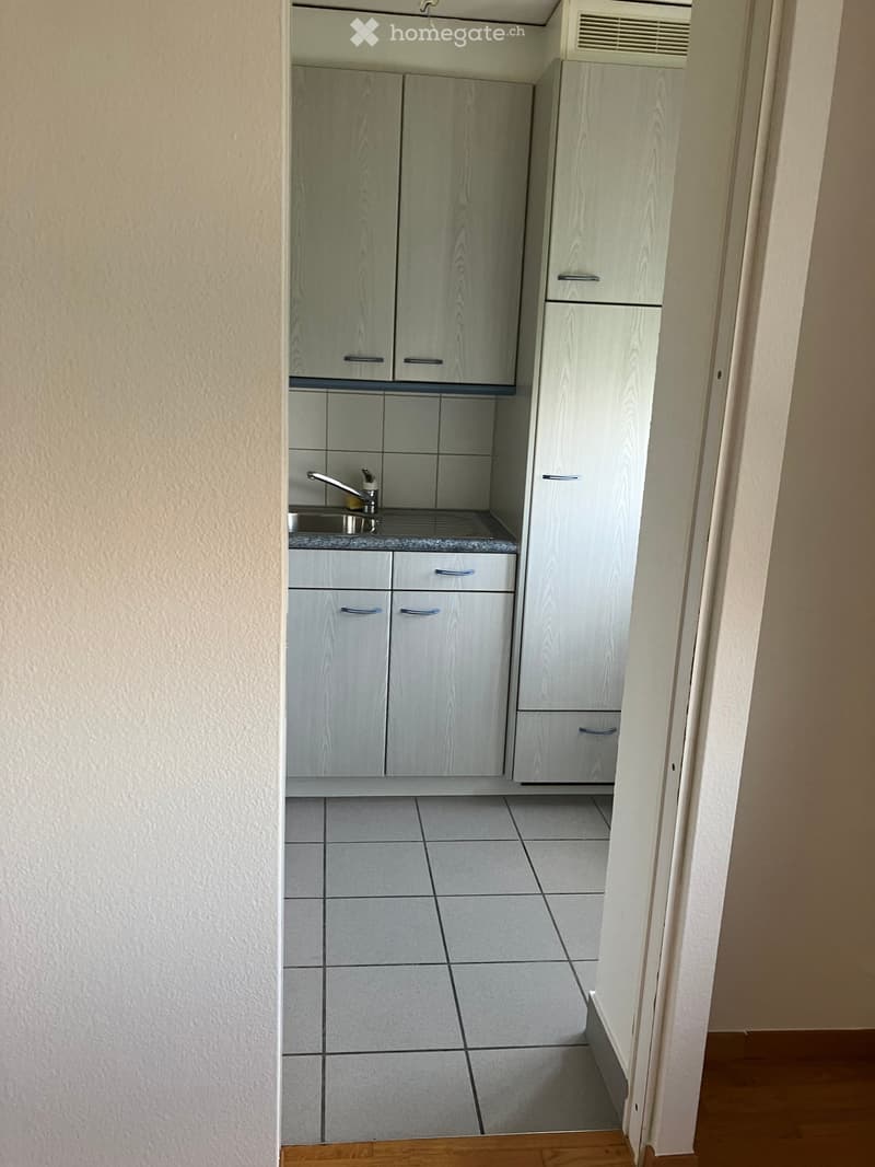 Compact kitchen with light wood cabinets, a sink, and tiled floor.