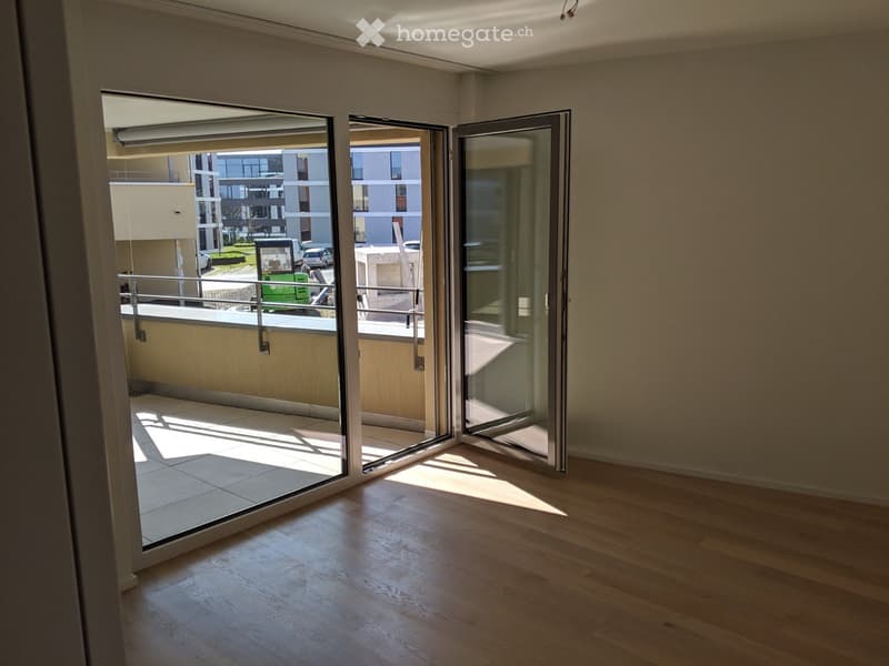 Empty room with wooden flooring and large glass sliding doors leading to a balcony area.